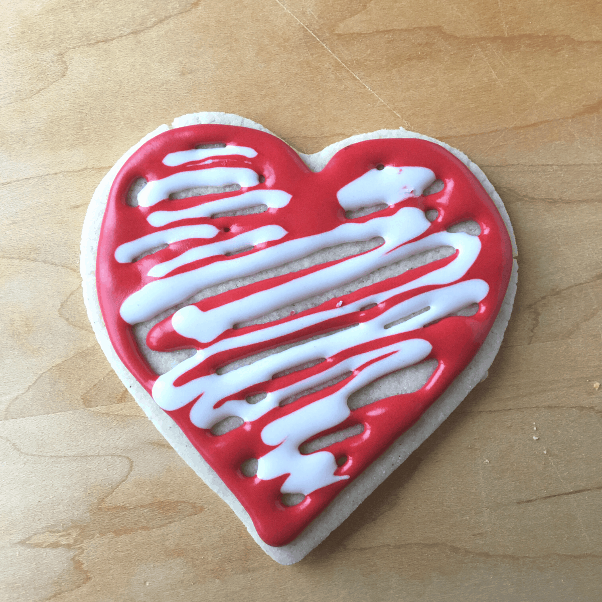 A heart sugar cookie with white and red vegan royal icing
