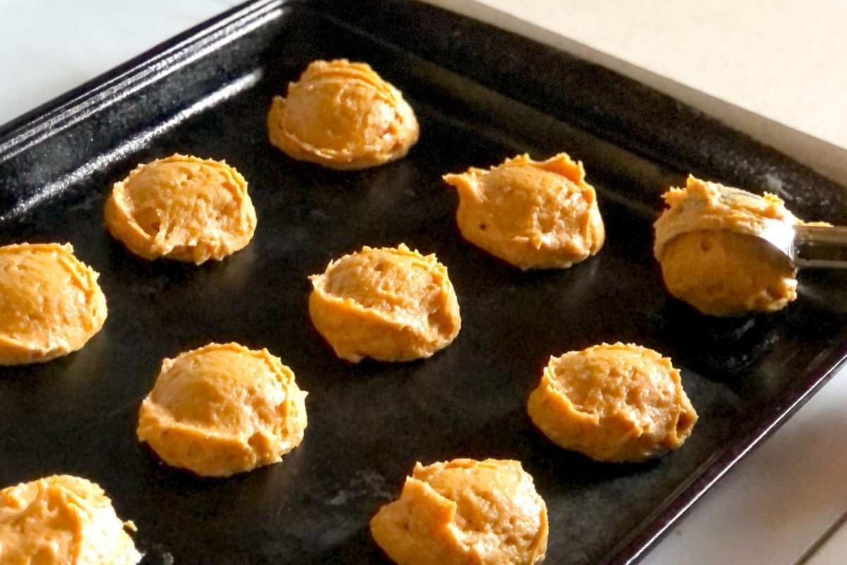 Gluten free pumpkin cookie dough being placed on a cookie sheet