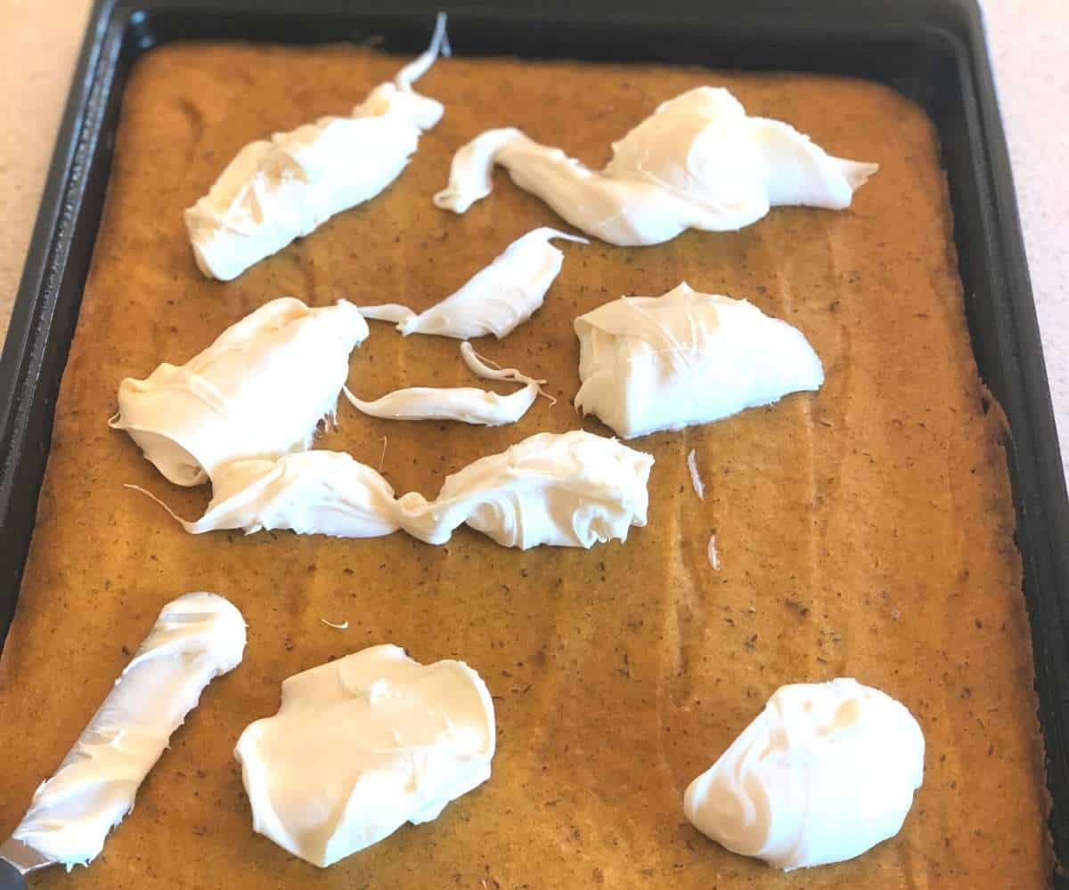 Blobs of frosting placed on pumpkin bars for easy spreading