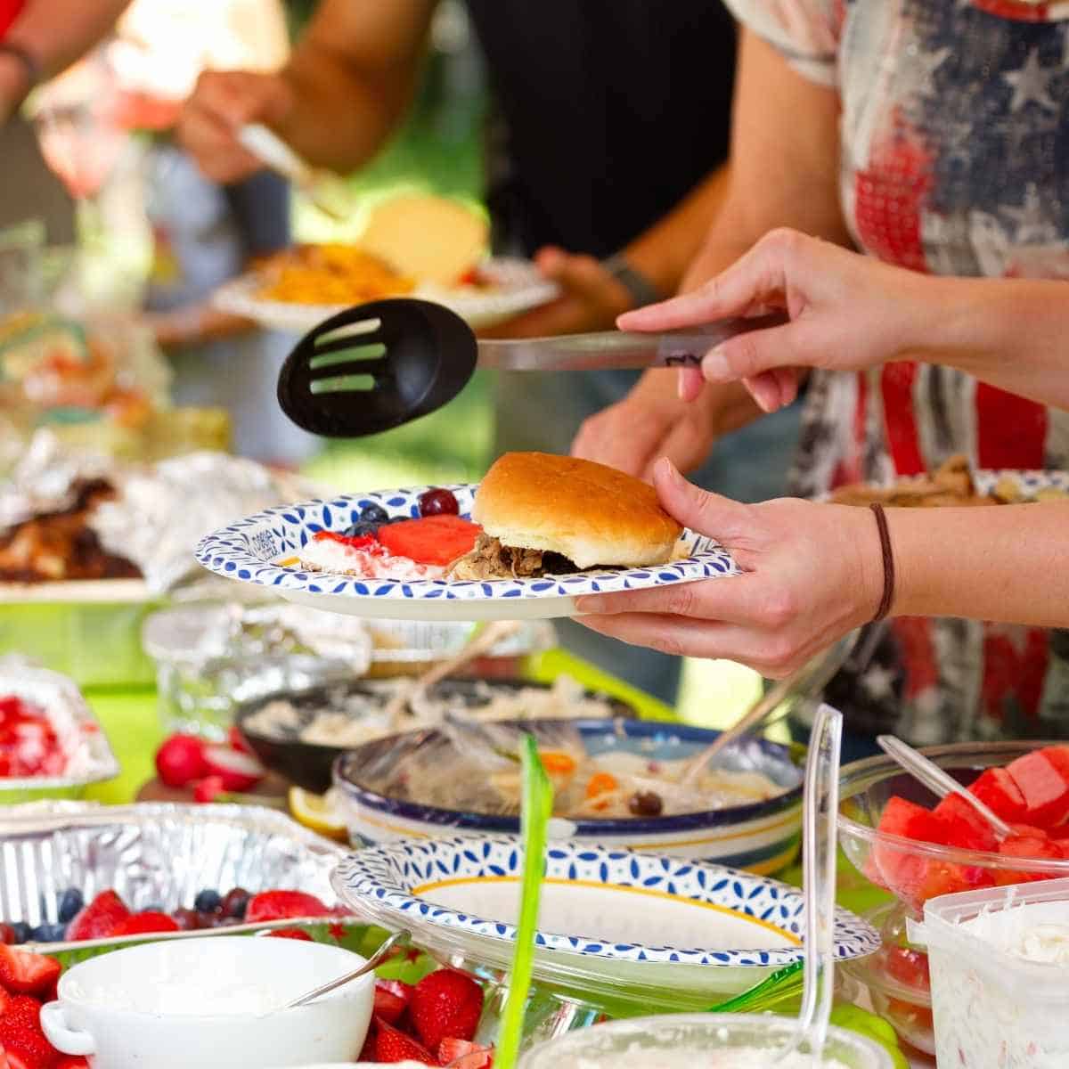 A person dishing up various foods at a buffet style gathering.