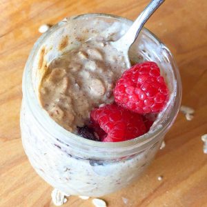 A jar of protein overnight oats with berries on top