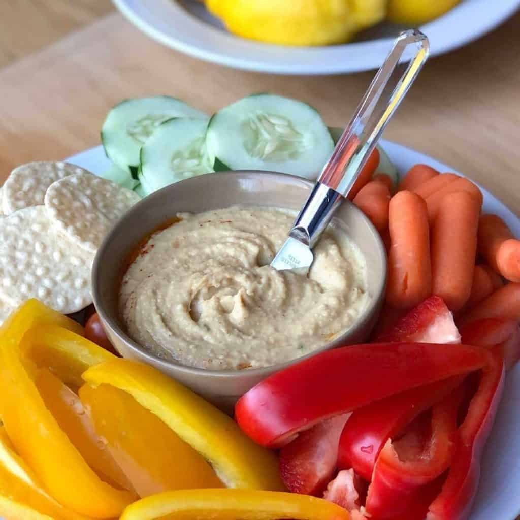 Gluten free hummus in a bowl surrounded by fresh vegetables