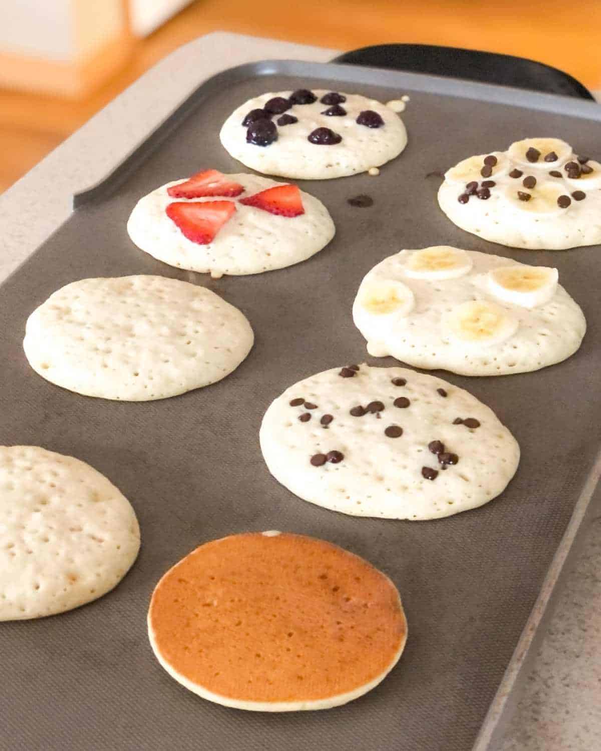 Oat milk pancakes being cooked on a griddle.
