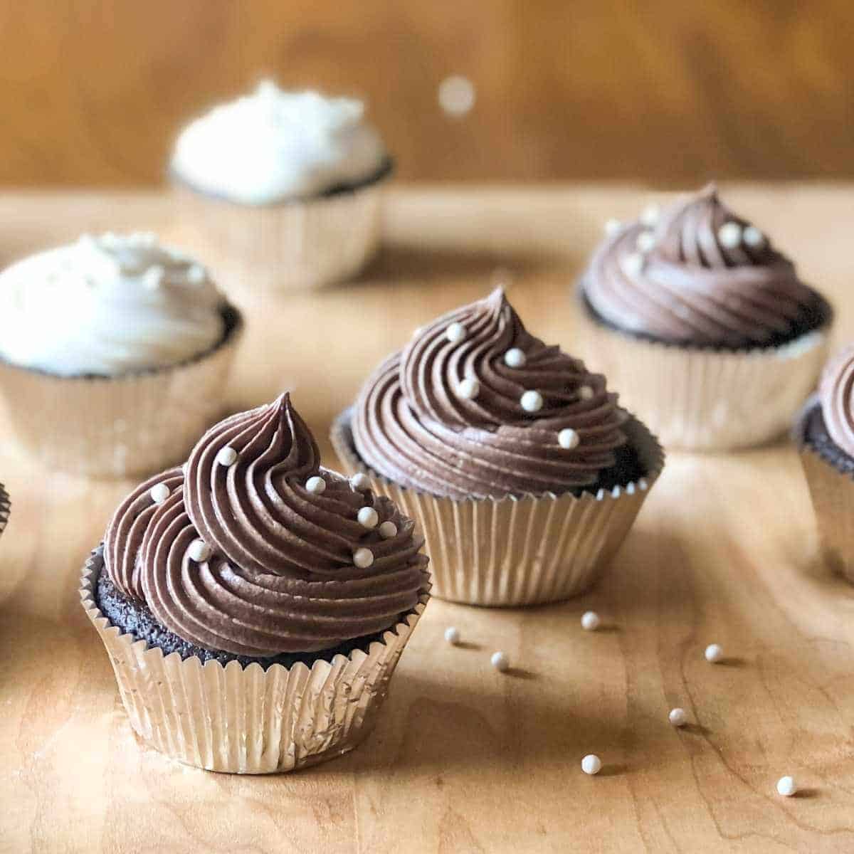 Chocolate gluten free cupcakes with chocolate frosting and white sprinkles.