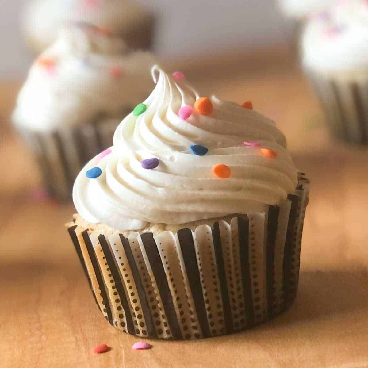 A cupcake topped with vanilla frosting and sprinkles.