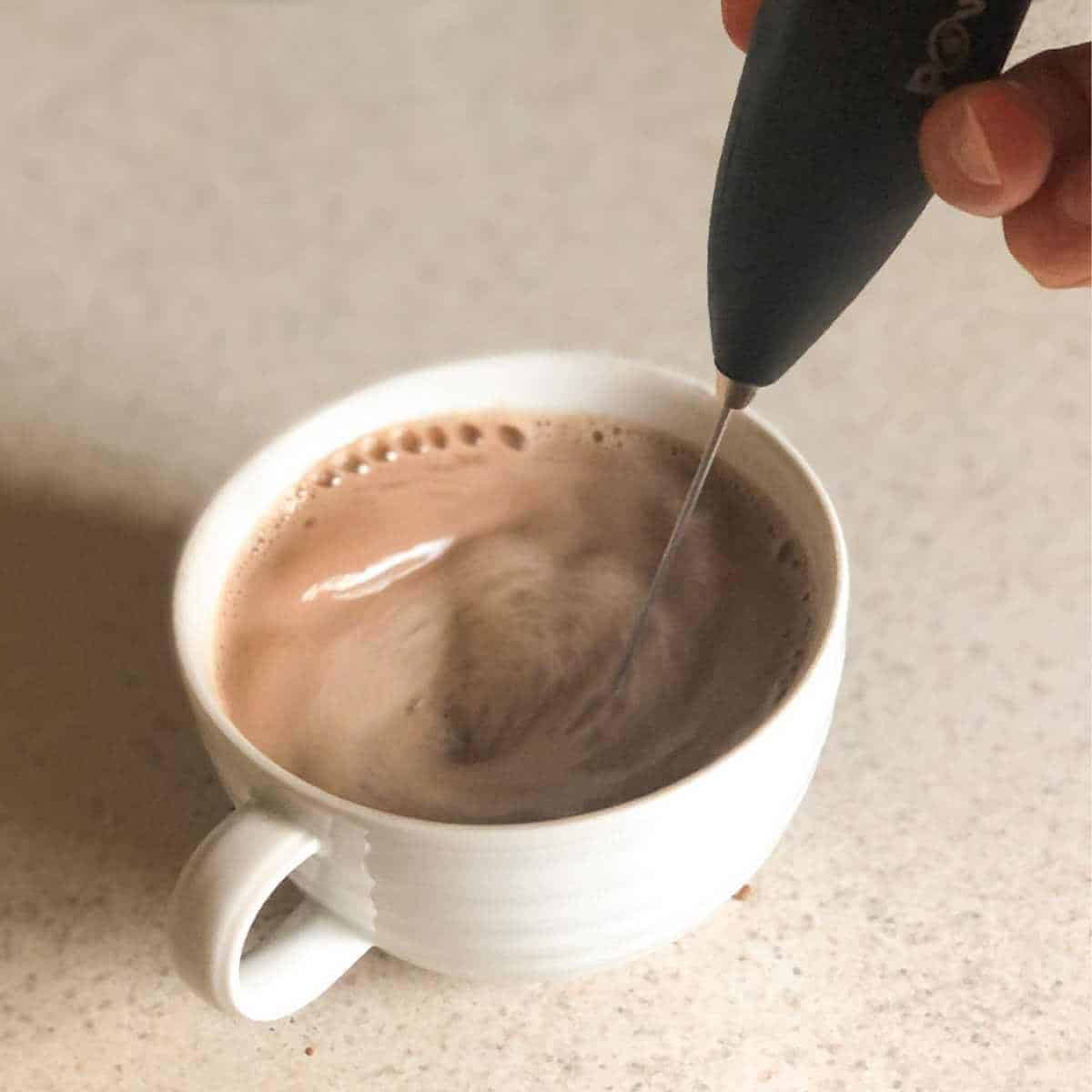 Oat milk hot chocolate being mixed with a frother