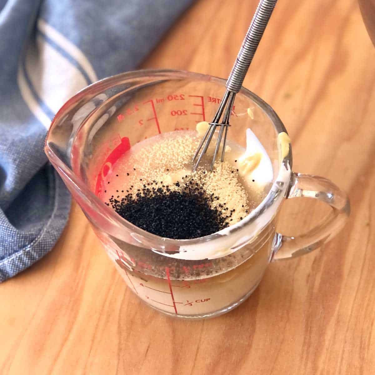 Vegan poppy seed dressing ingredients in a glass measuring cup.