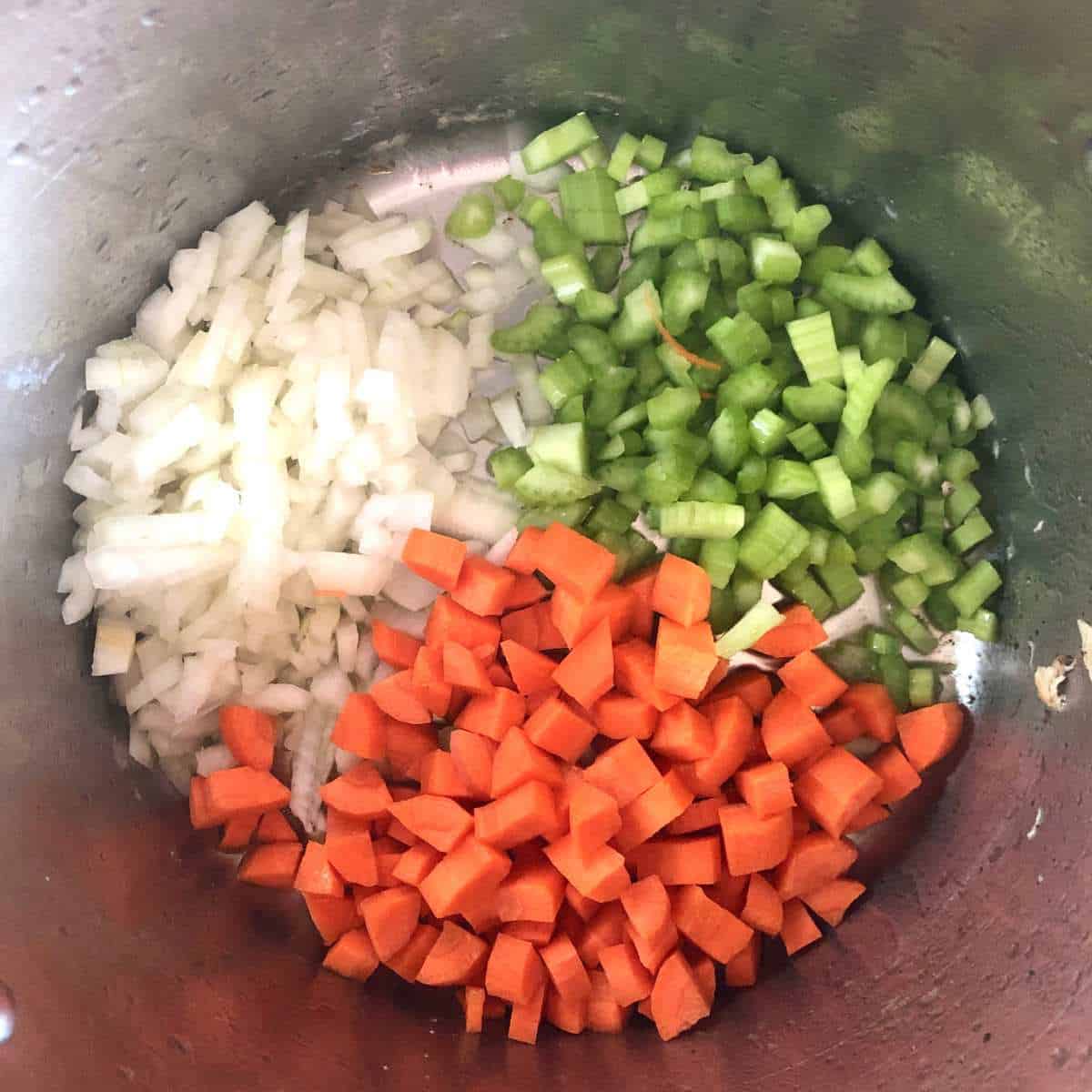Diced carrots, celery, and onions cooking in a stockpot