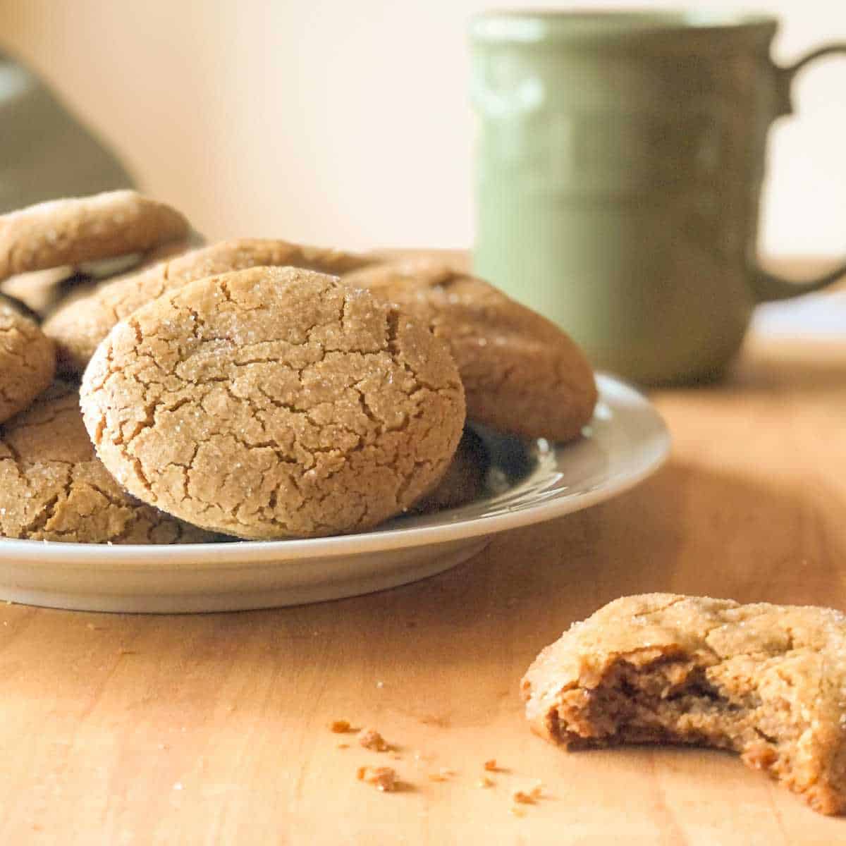 A plate of gluten free ginger cookies and one with a bite taken out of it.