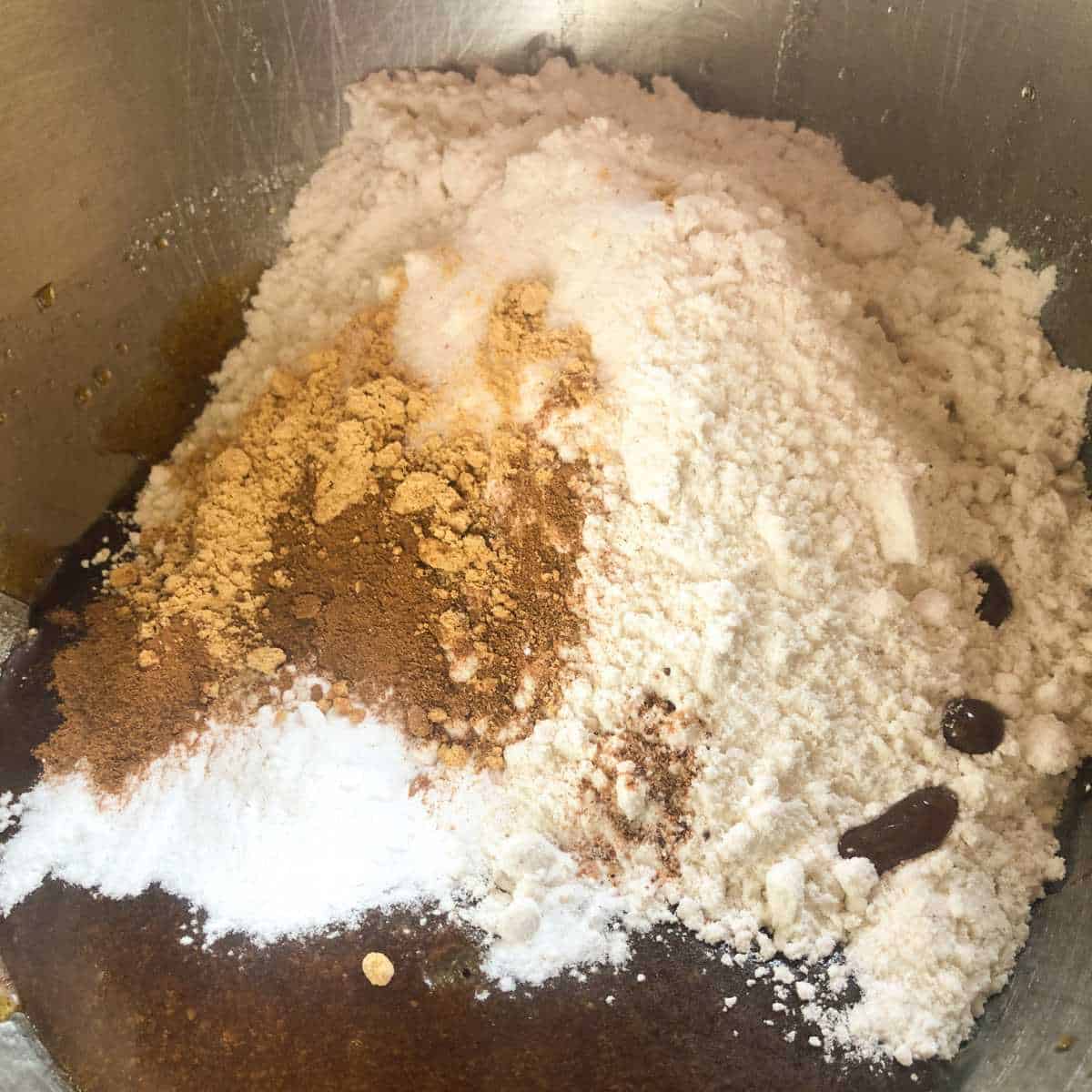 Gluten free flour, baking soda, salt, cinnamon, ginger, and nutmeg being mixed into wet cookie ingredients.