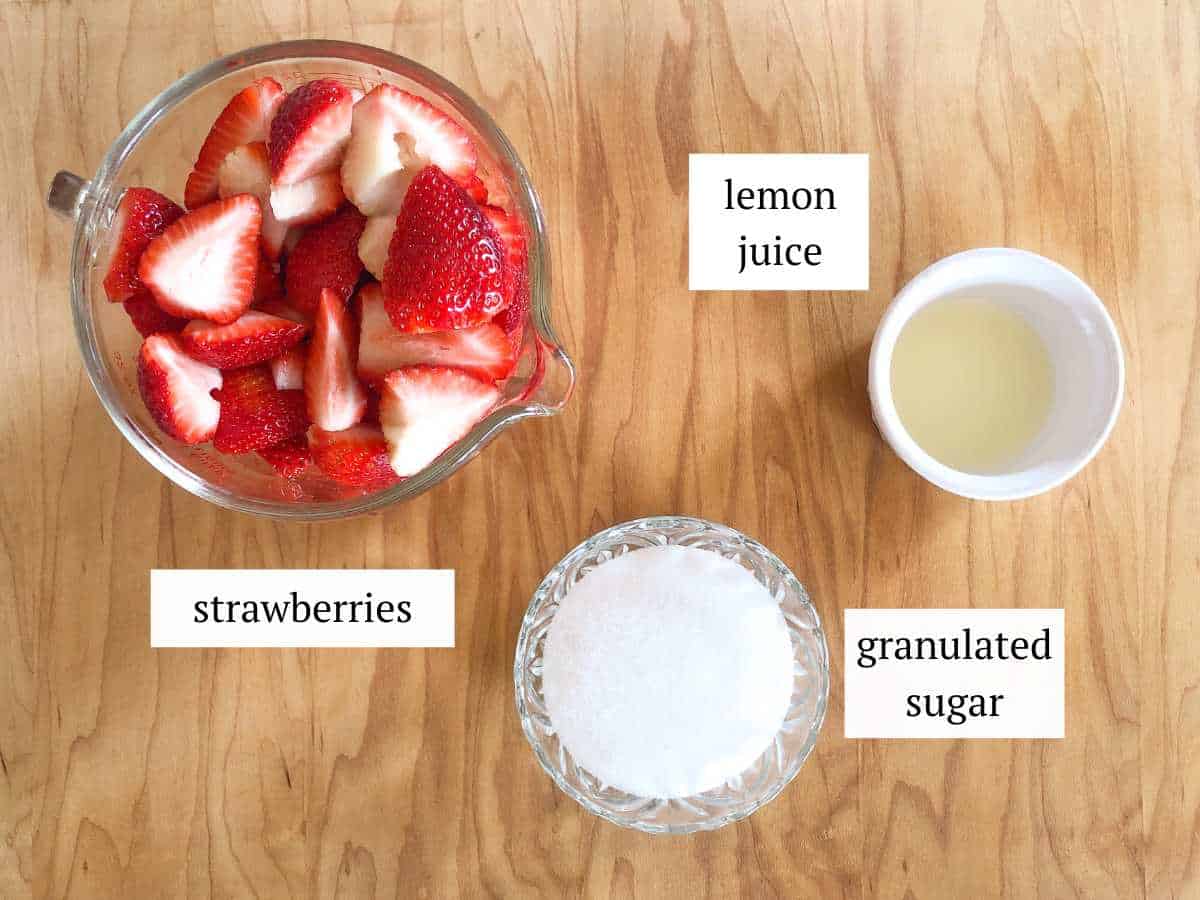 Strawberries, sugar, and lemon juice in bowls.