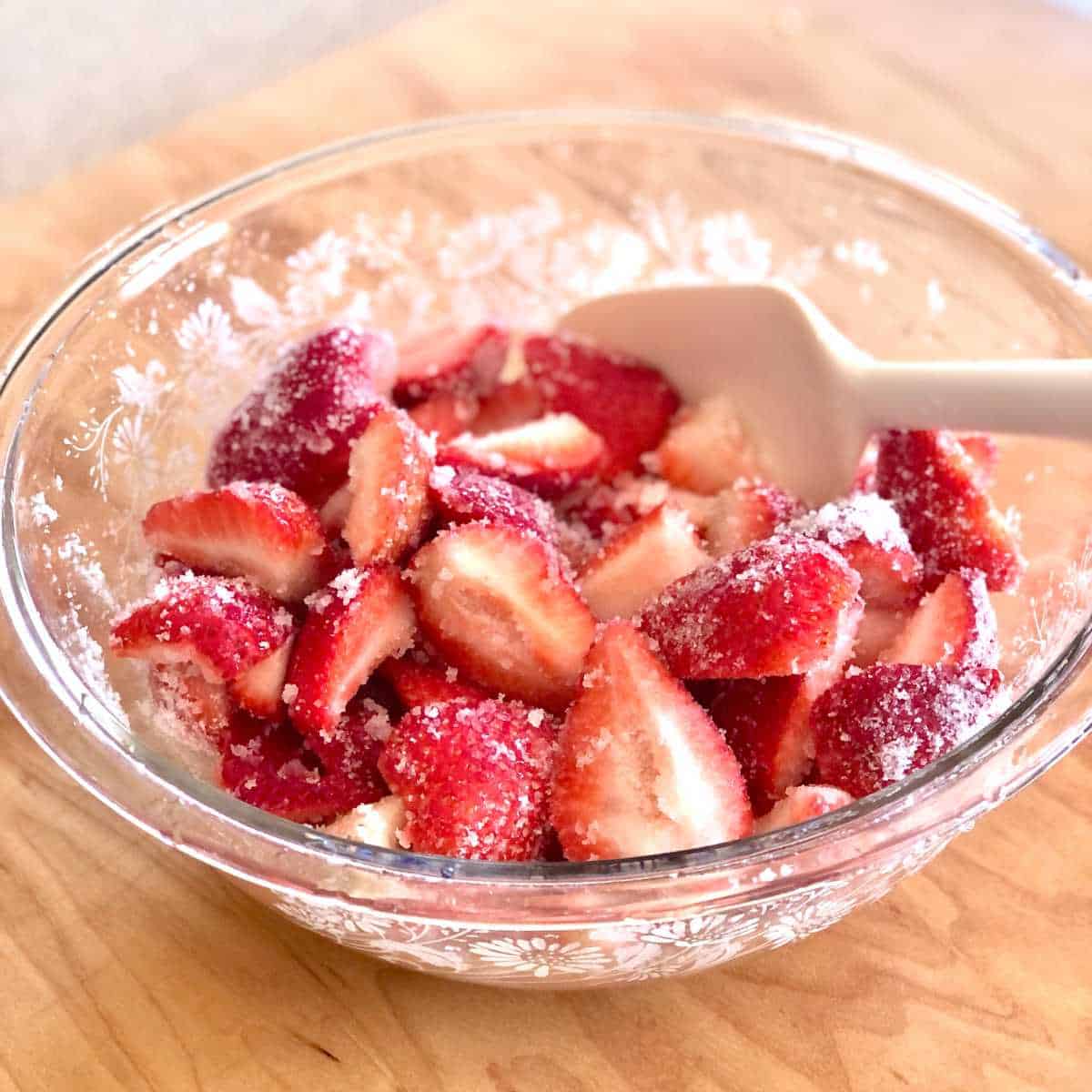 A bowl of strawberries coated in sugar