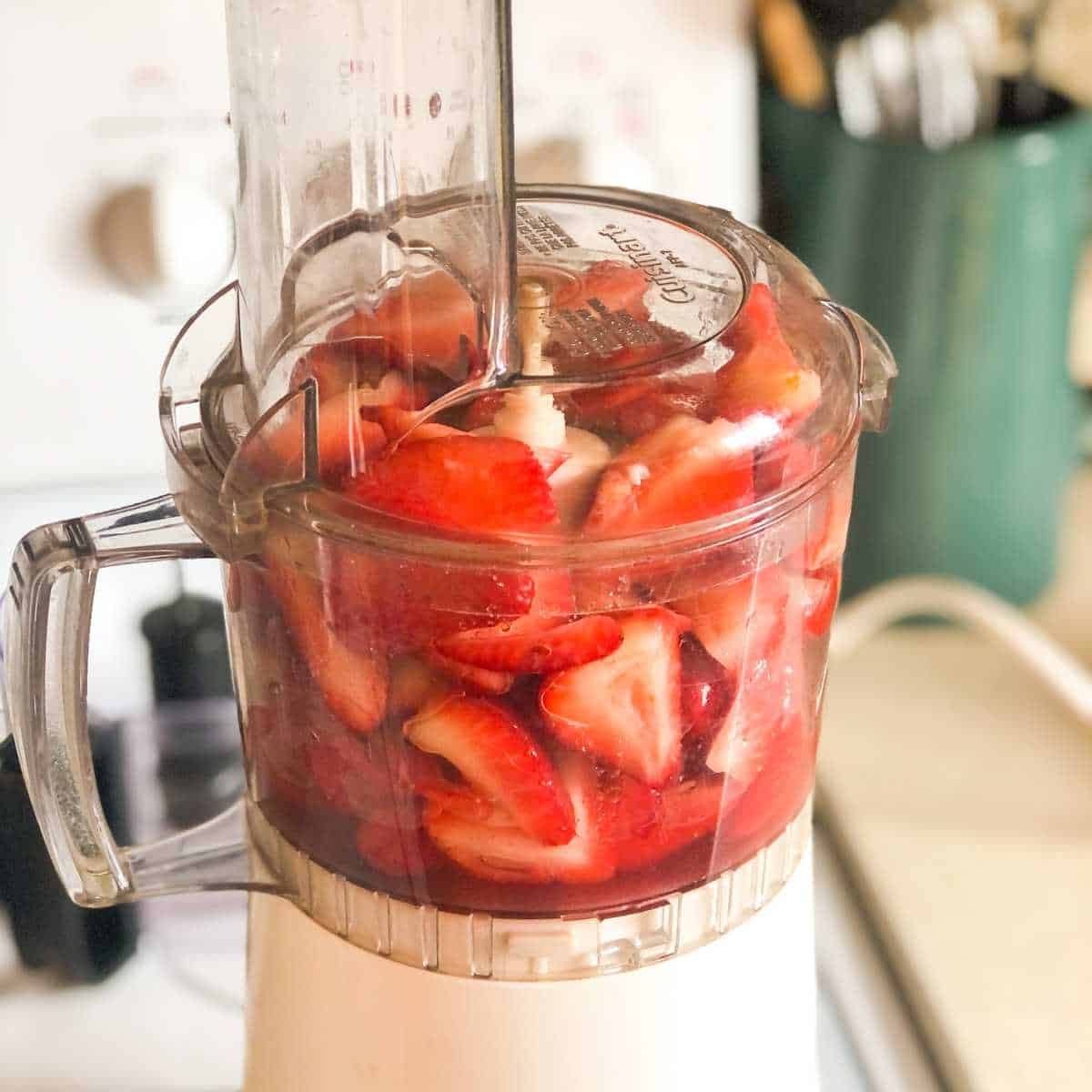 Strawberries and sugar in a food processor before pureeing.