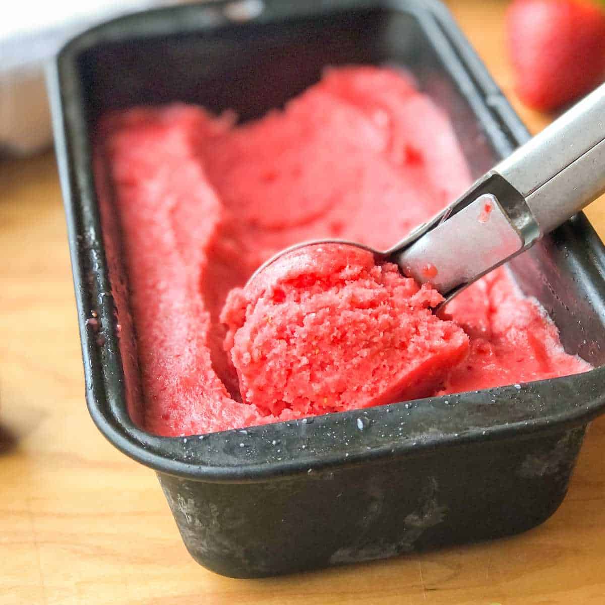 Dairy free sorbet being scooped out of a container with an ice cream scoop