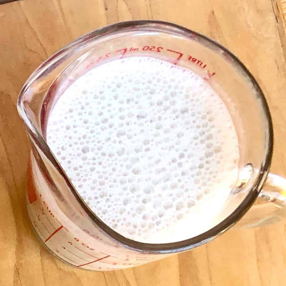 oat milk in a glass measuring cup.