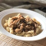 A bowl with gluten and dairy free turkey stroganoff on top of pasta