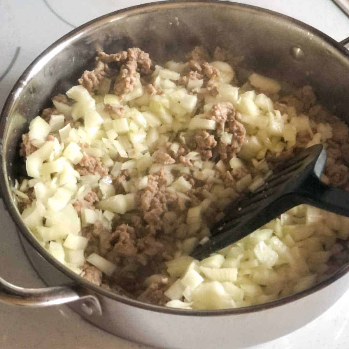 browned ground turkey being cooked with chopped onions in a skillet