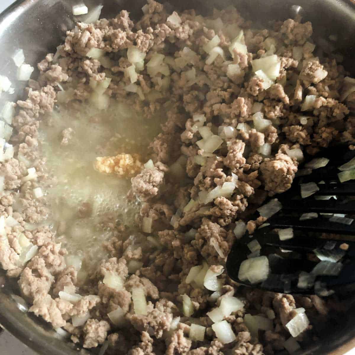 browned ground turkey in a skillet with minced garlic added