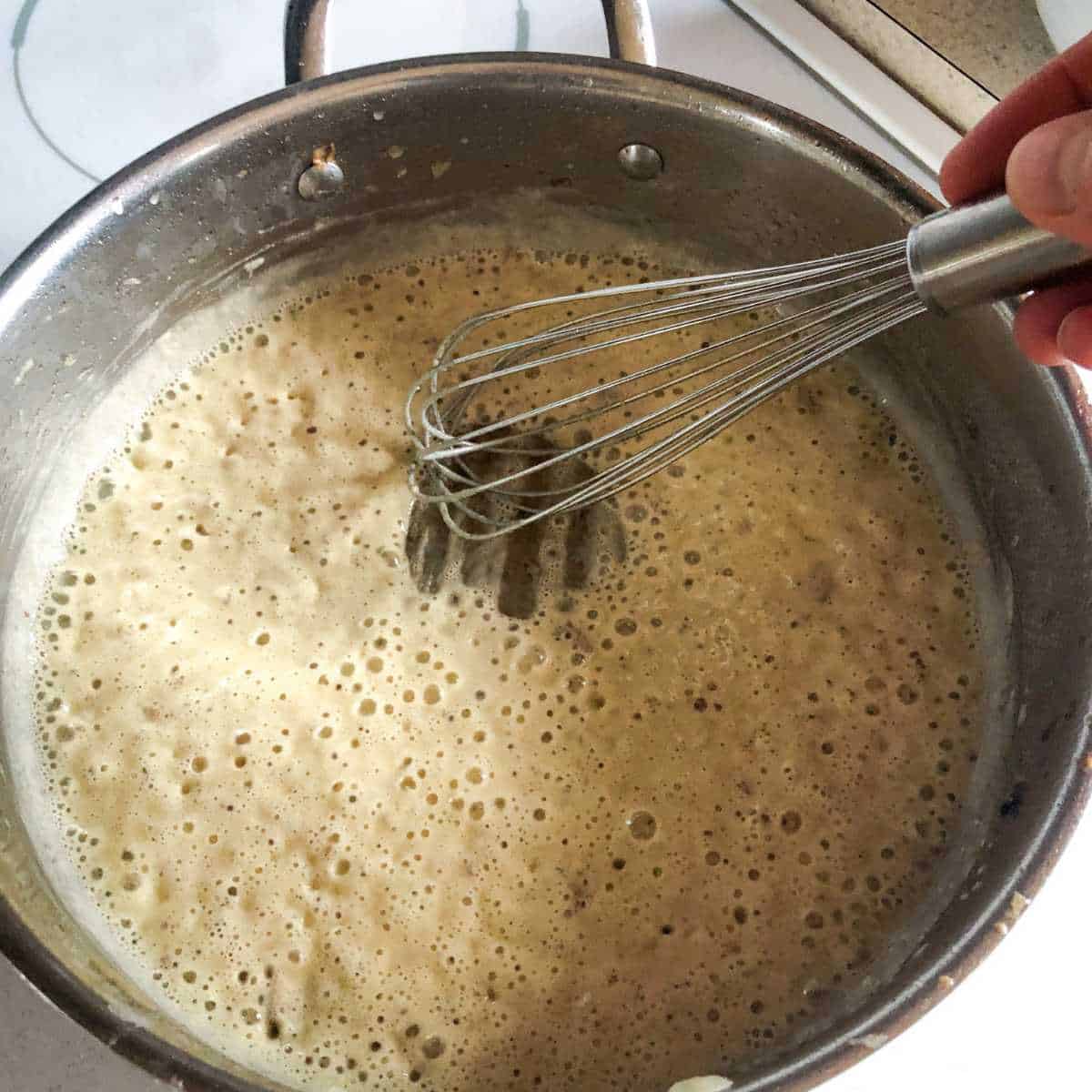A mixture of melted dairy free butter and gluten free flour being cooked over medium heat in a skillet.