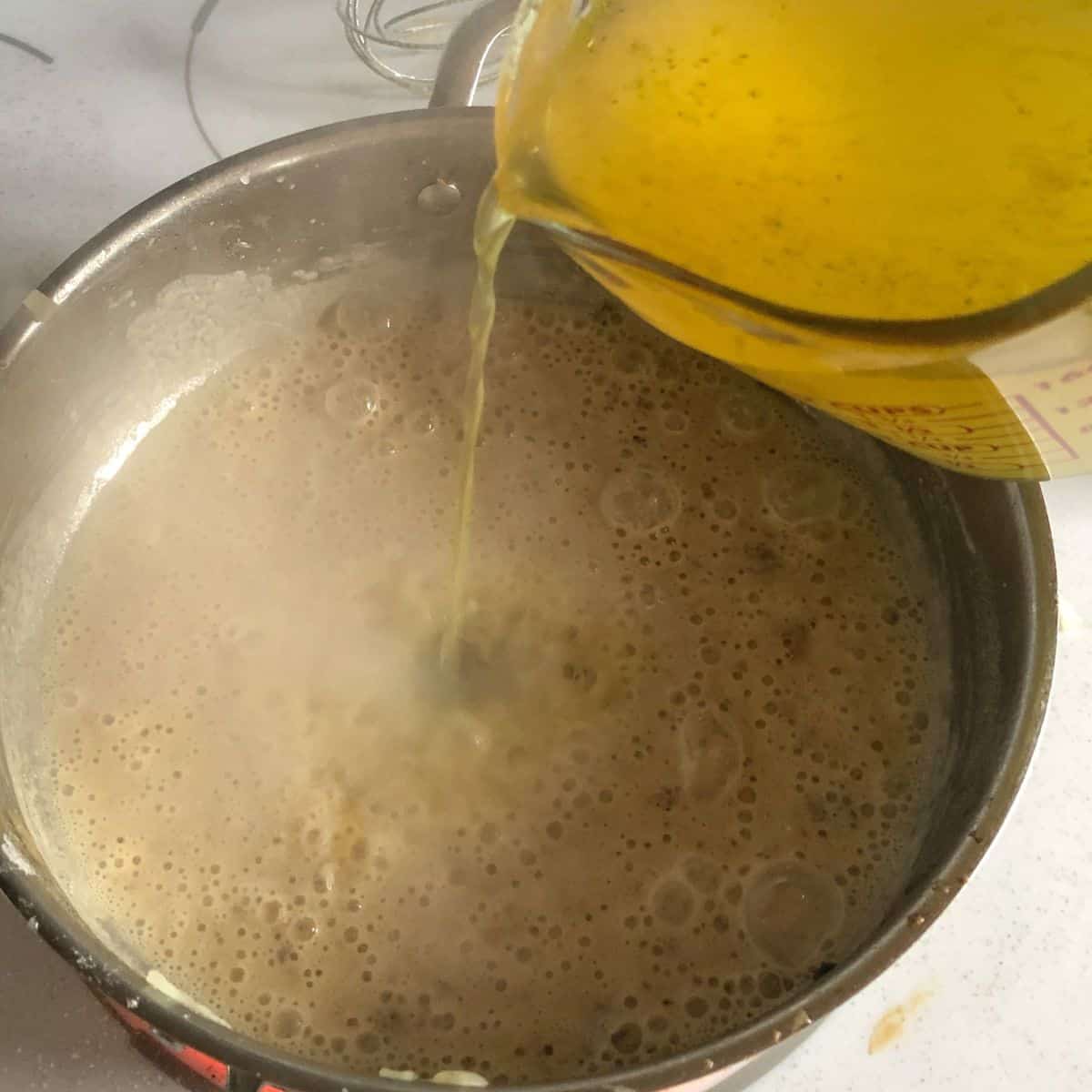 Chicken broth being whisked into the gluten free flour and dairy free butter mixture.