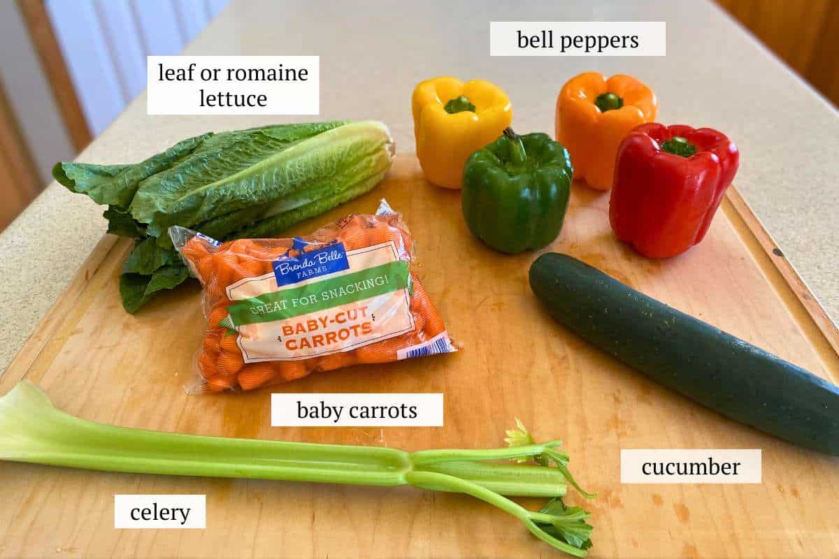 Ingredients to make a turkey veggie tray including lettuce, baby carrots, a celery stalk, a cucumber, and bell peppers.