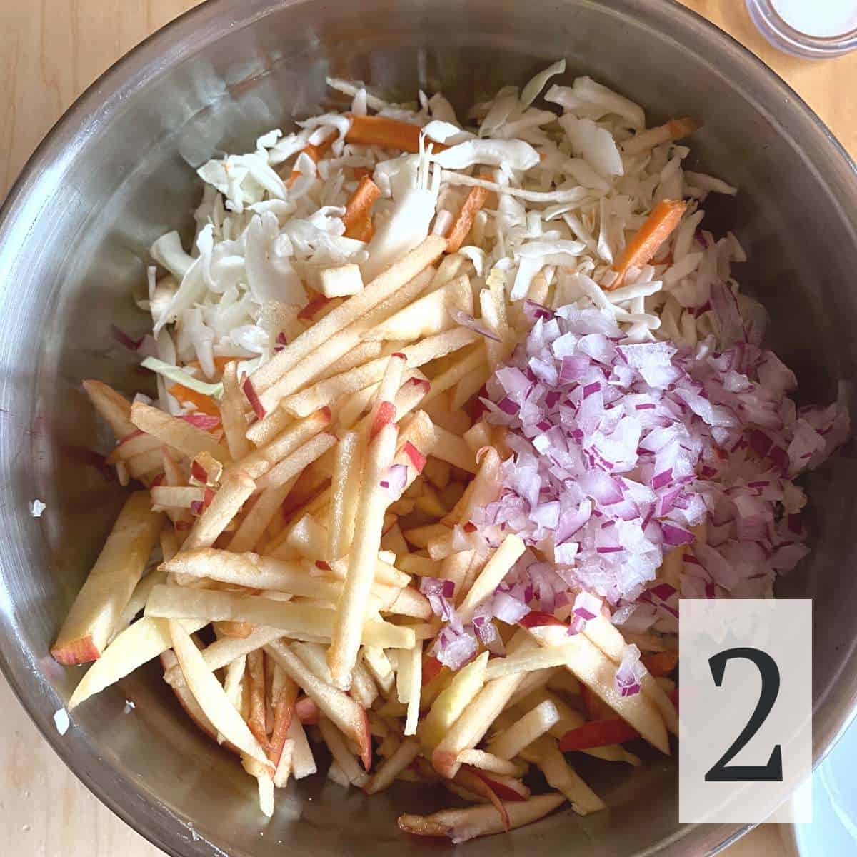 sliced apples, diced red onion, and cole slaw mix in a bowl.