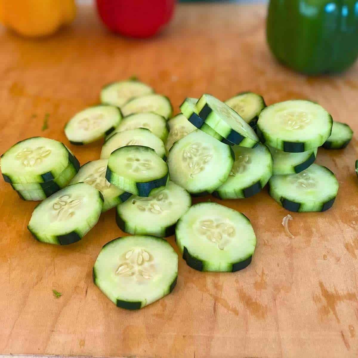 Cucumbers sliced into coins on a cutting board.