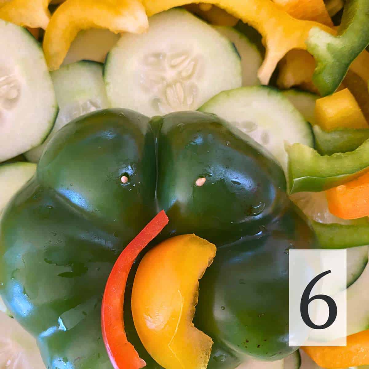 The end of a bell pepper forming the face of the turkey with a red pepper snood and yellow pepper nose and toothpicks to hold the eyes.