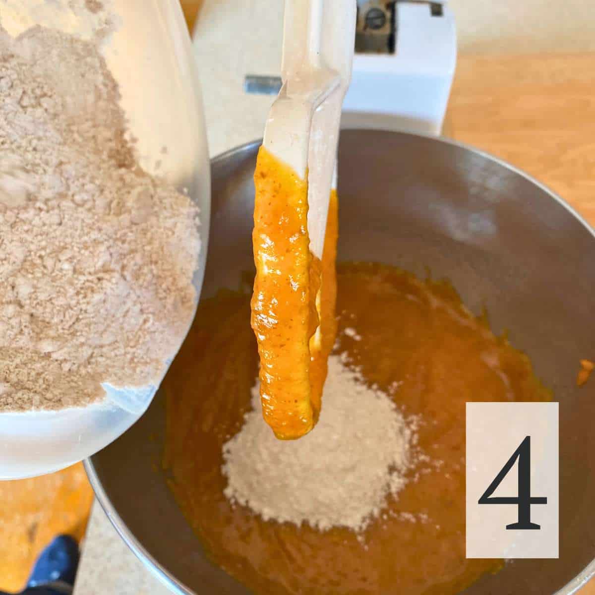 Gluten free flour mixture being added to the mixing bowl containing wet ingredients.
