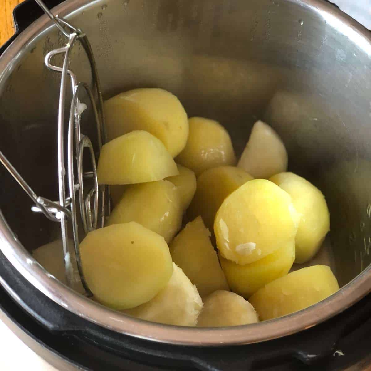 Cooked potatoes in a pressure cooker pot with the trivet being removed.