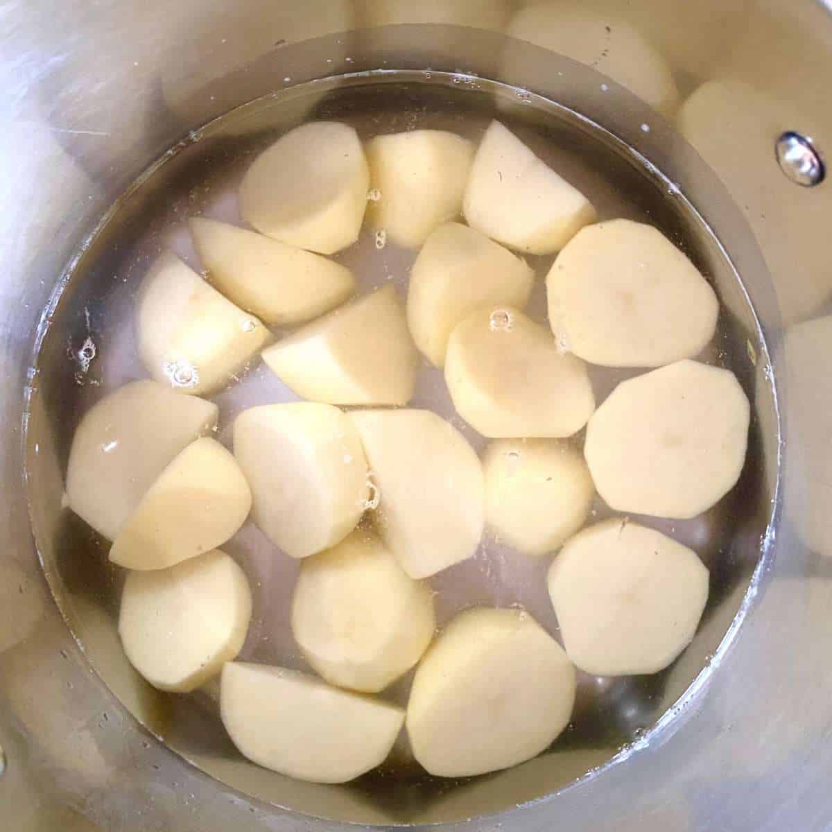 cut up potatoes covered in water in a stock pot.
