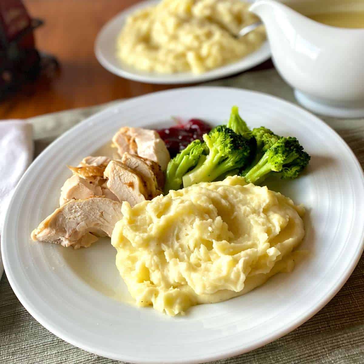 A dinner plate with dairy free mashed potatoes, roasted turkey, cranberry sauce, and broccoli.