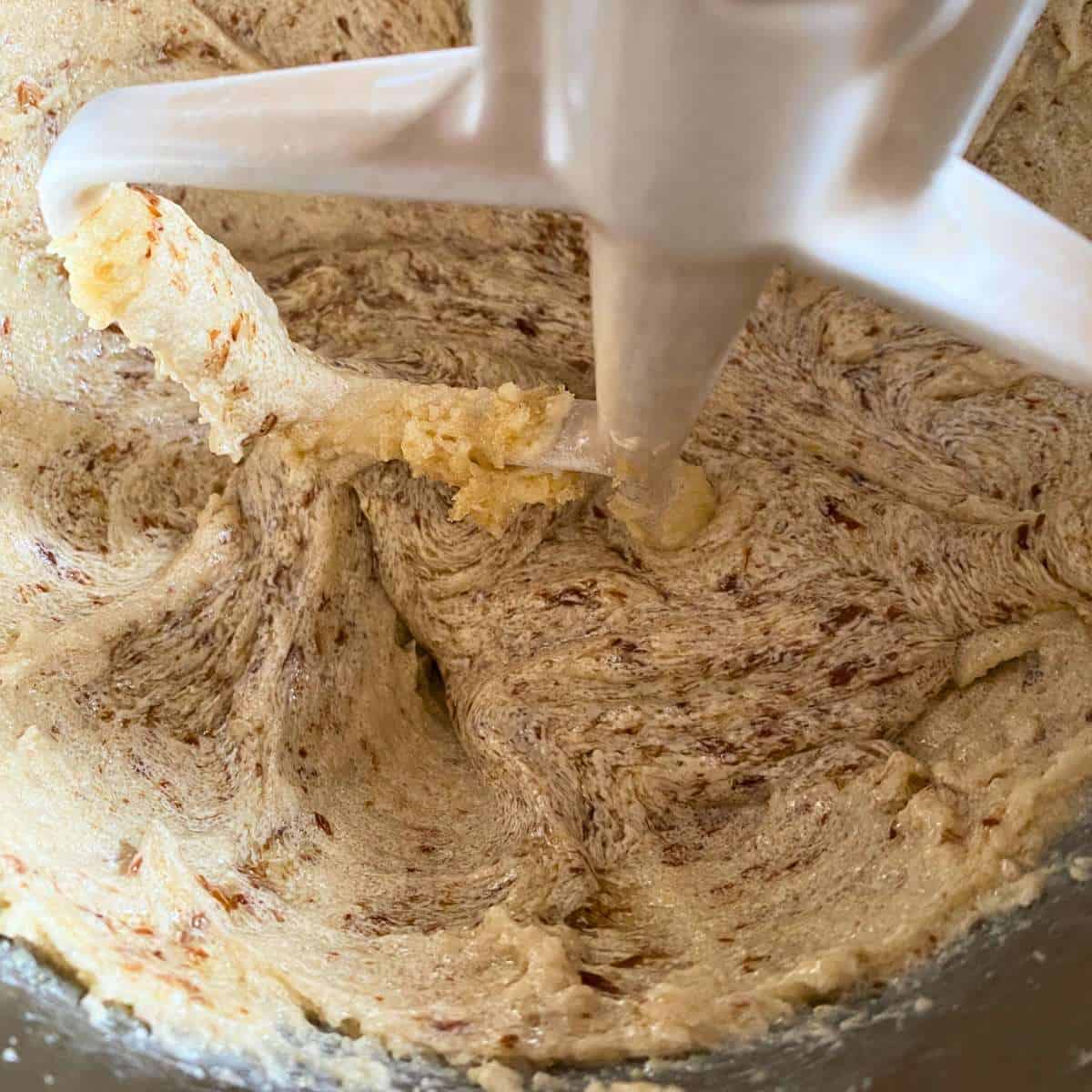 Sugar, margarine, flax "egg" and vanilla extract being mixed together in a stand mixer bowl.