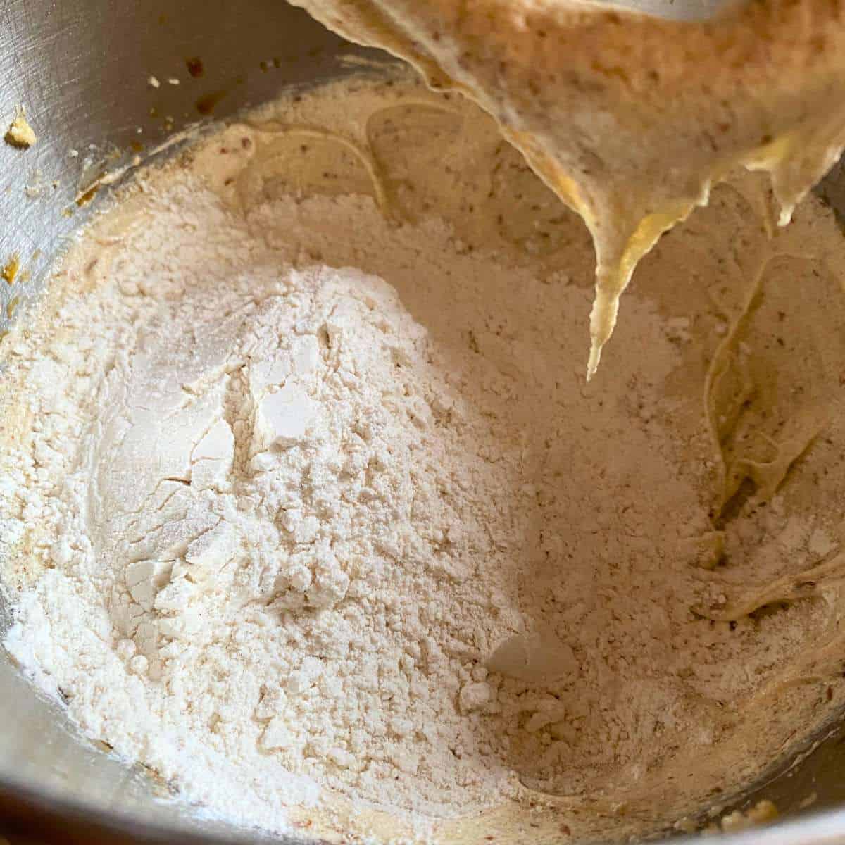 The gluten free flour mixture being added to the sugar and margarine mixture in a mixing bowl