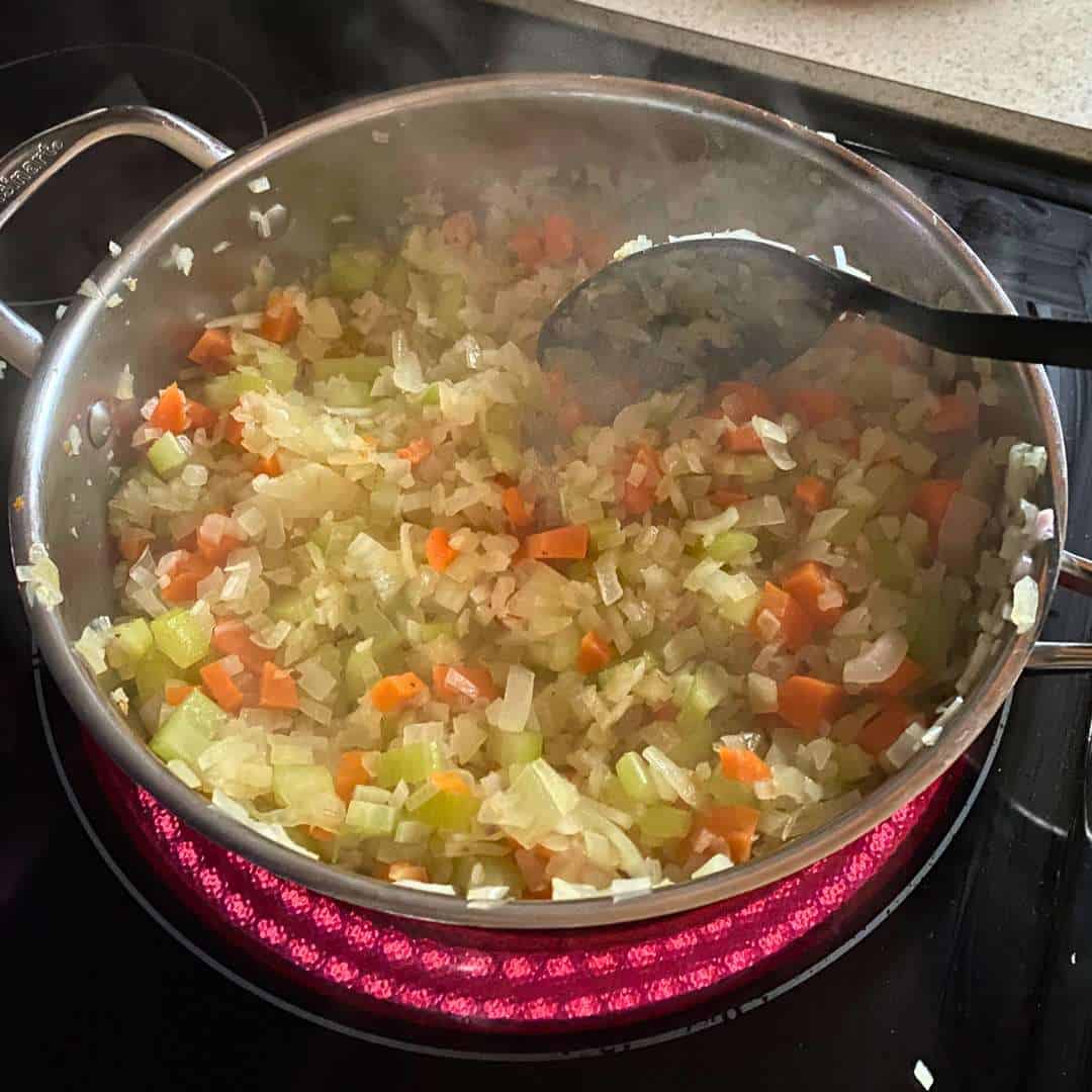 Cooked carrots, onions, celery, and shallots in a skillet.